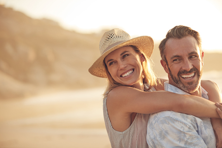 Youthful looking couple hugging on beach at sunset